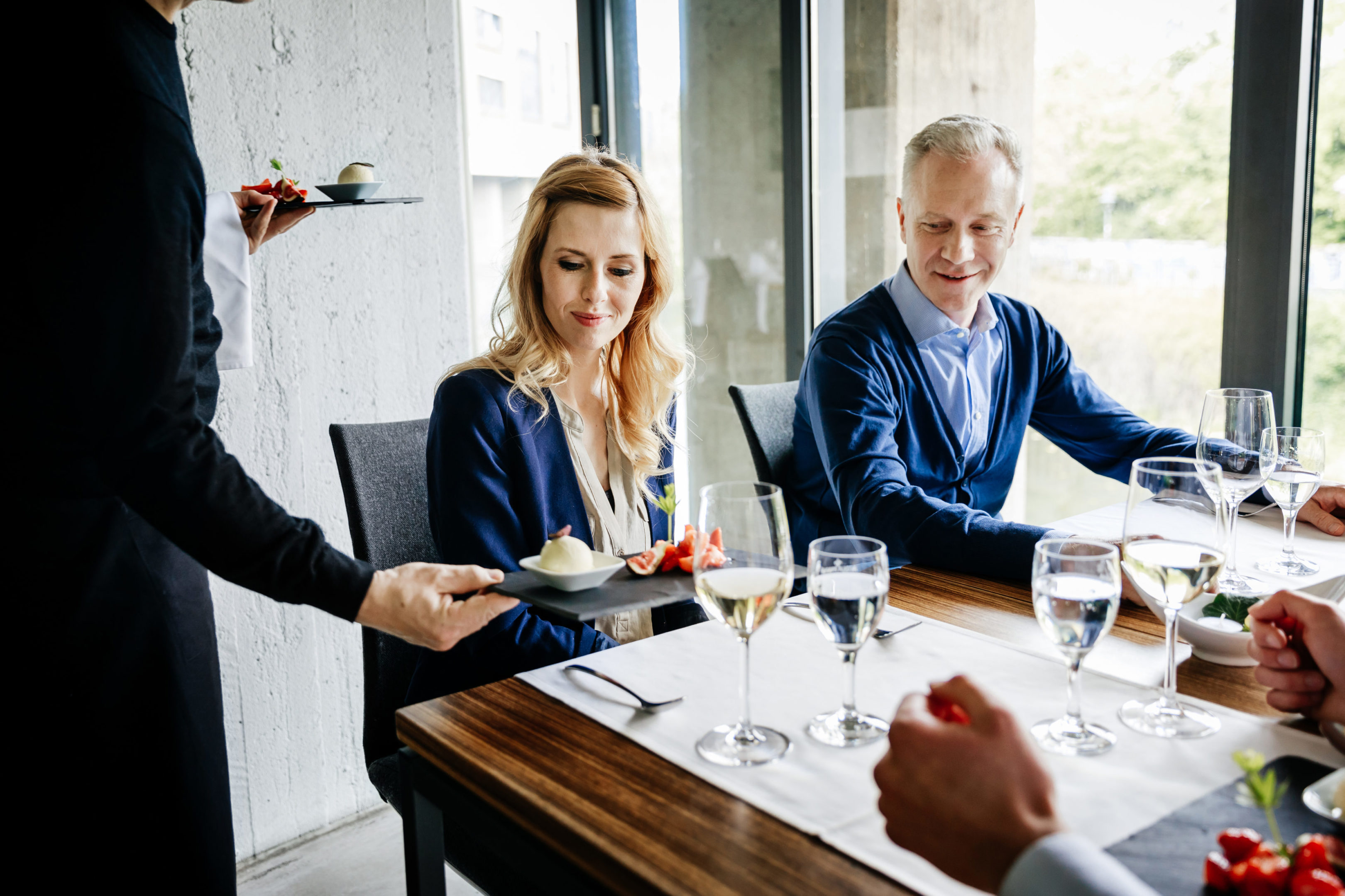Waiter Serving Food To Patrons Having Business Lunch Together A waiter is serving food to a group of business colleagues having lunch together.